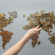 World map made of coins with a magnifying glass, representing globally diversified investing
