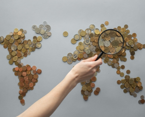 World map made of coins with a magnifying glass, representing globally diversified investing