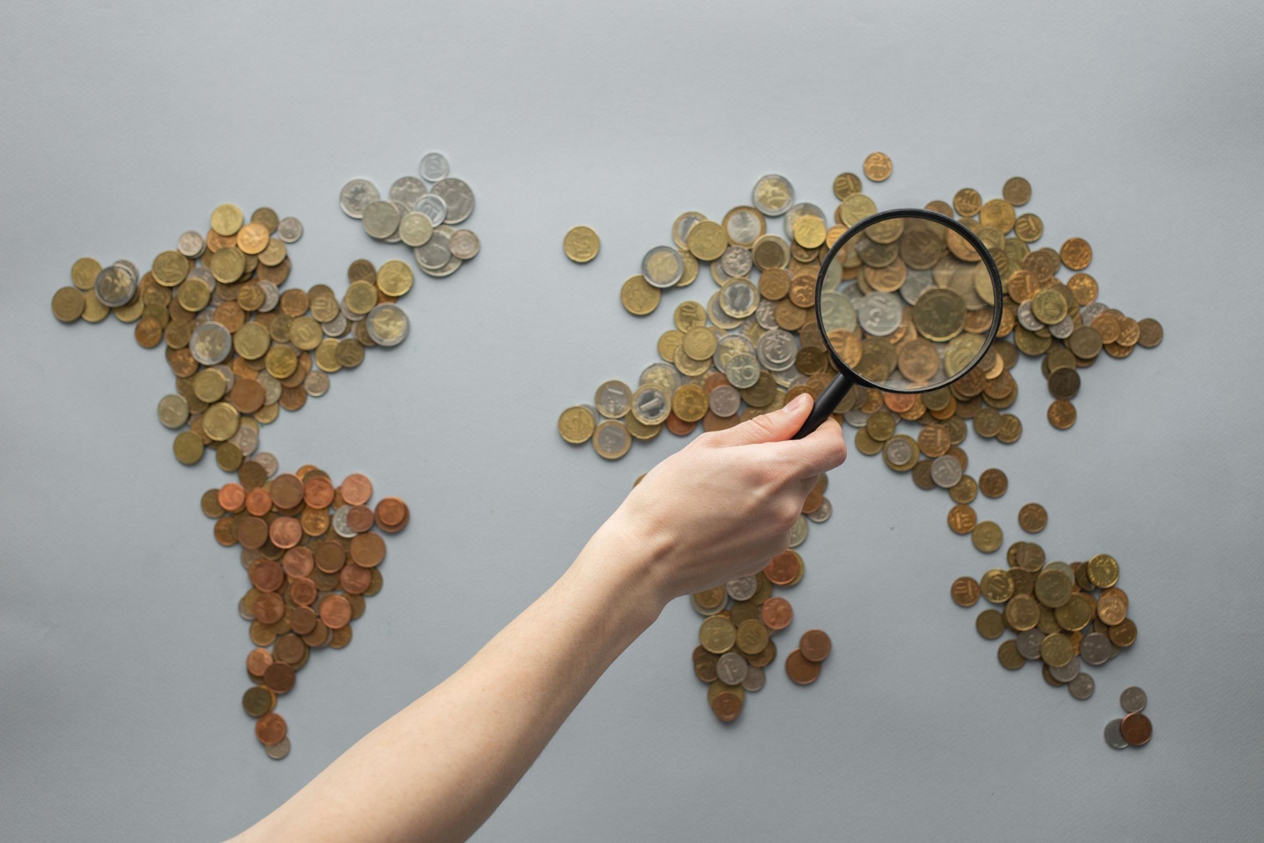 World map made of coins with a magnifying glass, representing globally diversified investing
